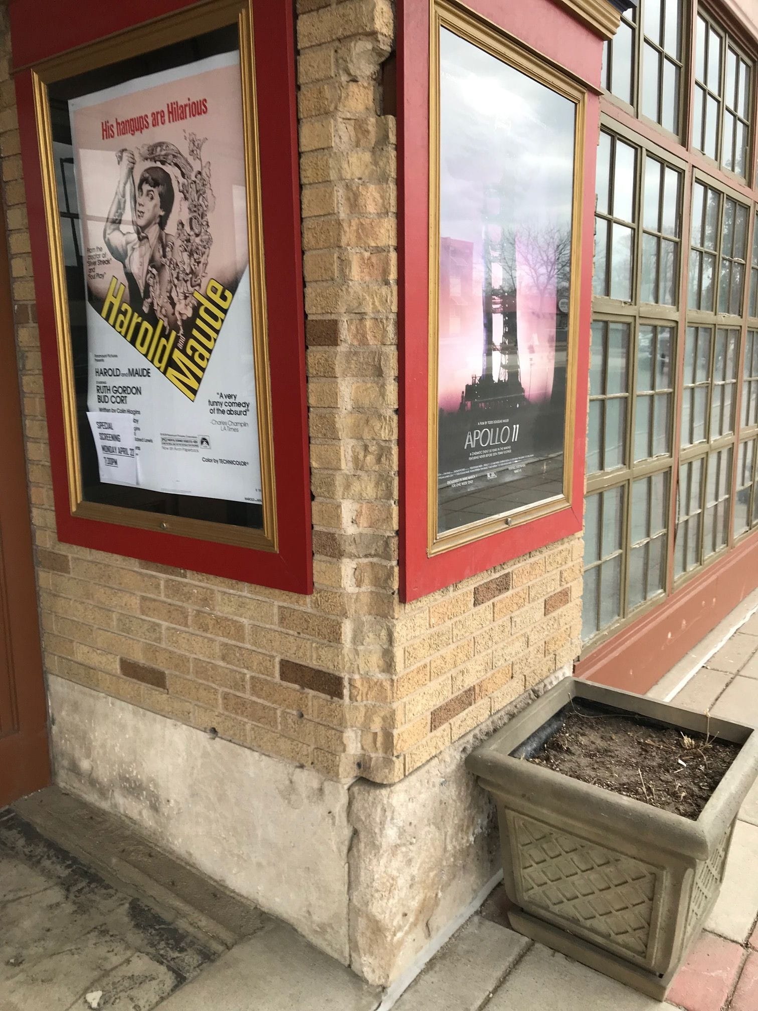 The exterior stone corner of Heights Theater with movies Apollo II and Harold and Maude displayed in red frames.